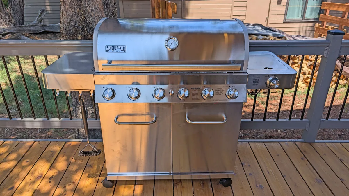 A spacious wooden deck with a built-in grill, surrounded by natural elements and featuring plenty of room for outdoor dining and social gatherings. The area is designed to accommodate groups, making it ideal for barbecues or social hours while soaking in the surrounding views.