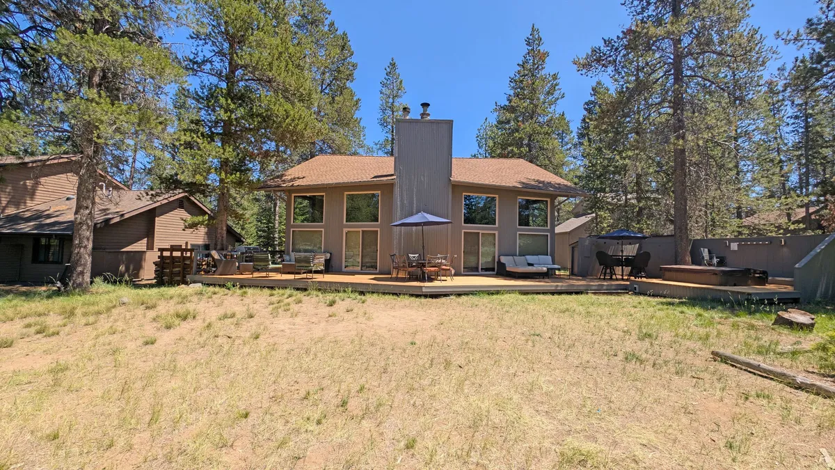 This image presents a view of the home’s large windows, the expansive deck area, and a lush frame of surrounding trees. It conveys a sense of openness, inviting guests to unwind outdoors or simply take in the beauty of Sunriver, making it an ideal visual anchor for an exploration-themed section.